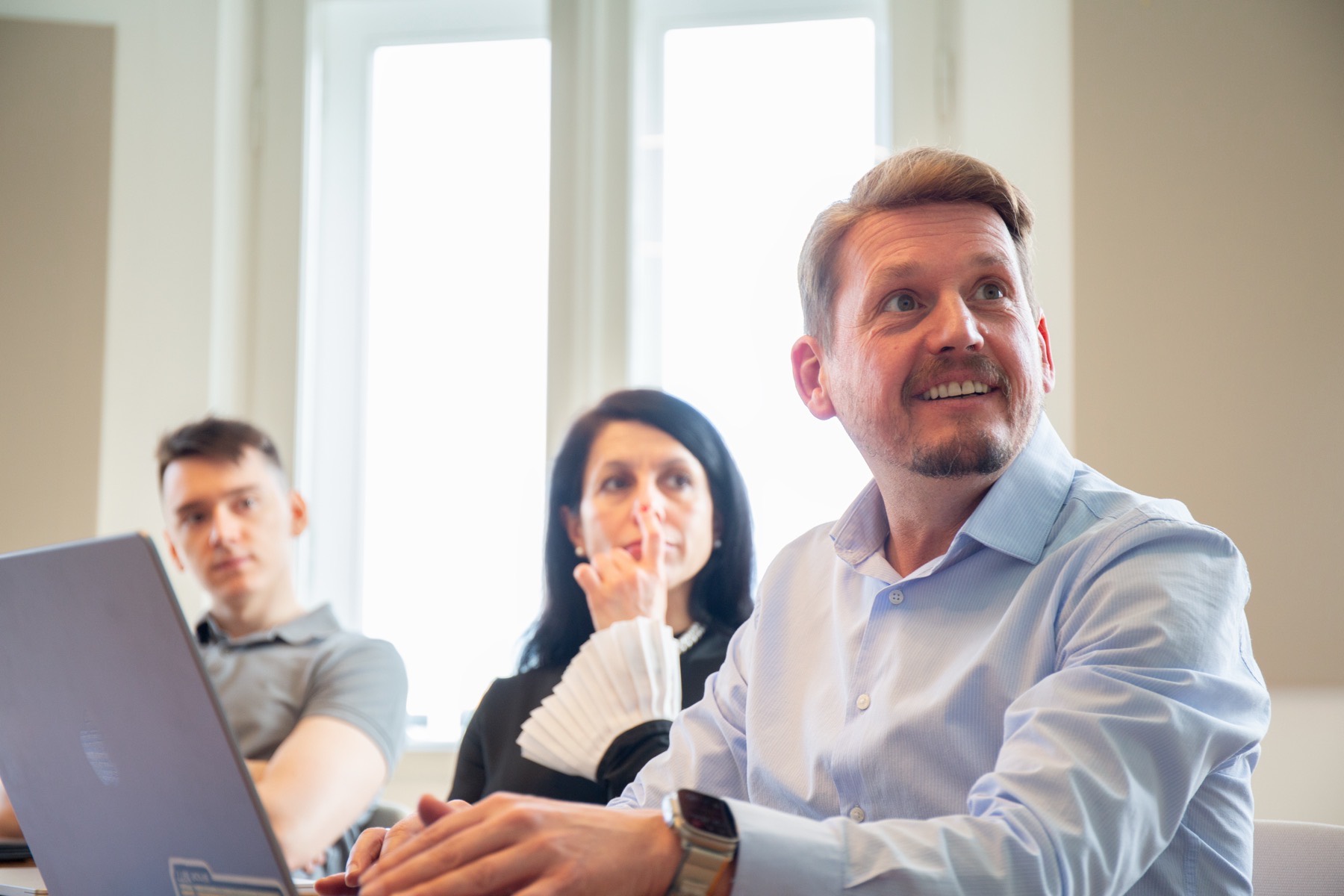 Colleagues listening and taking notes during a working session in the office.
